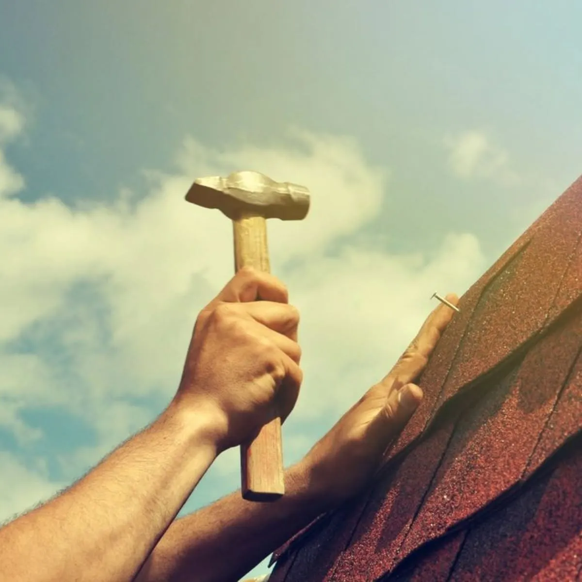 Roofer hand-nailing asphalt shingles during roof repair in Spring Valley, CA